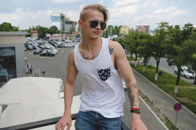 Hipster handsome blonde man guy in stylish summer clothes in the street