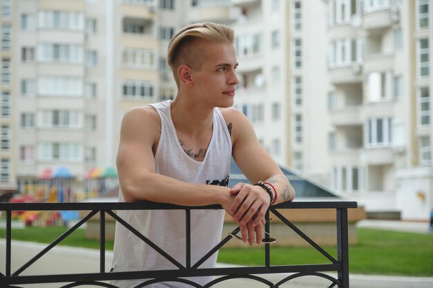 Hipster handsome blonde man guy in stylish summer clothes in the street