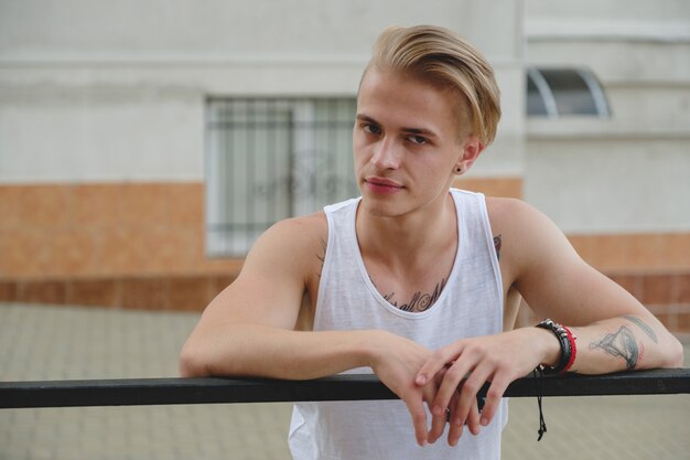 Hipster handsome blonde man guy in stylish summer clothes in the street