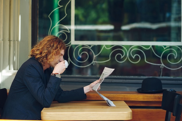 Foto gratuita uomo hipster che beve caffè durante la lettura