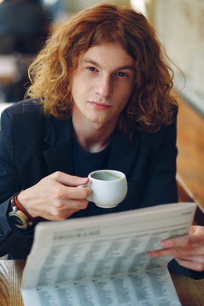 Foto gratuita uomo hipster che beve caffè durante la lettura