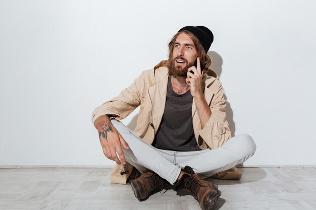 Hipster man looking aside sitting isolated over wall