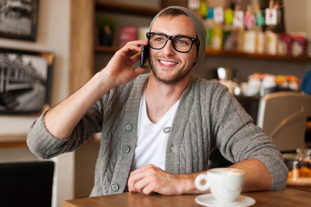 Hipster 남자 카페에서 휴대 전화로 이야기