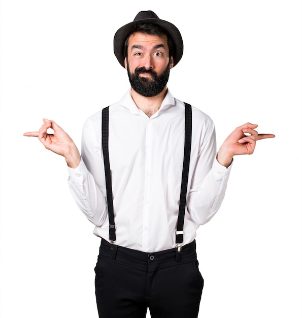Hipster man with beard pointing to the laterals having doubts