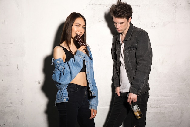 Free photo hipster man with beer near girlfriend eating chocolate