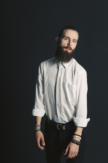 Hipster style bearded man white shirt in studio over black background