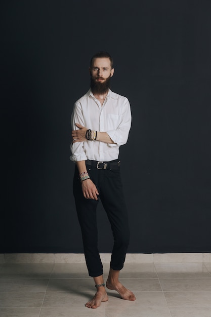 Hipster style bearded man white shirt in studio over black background