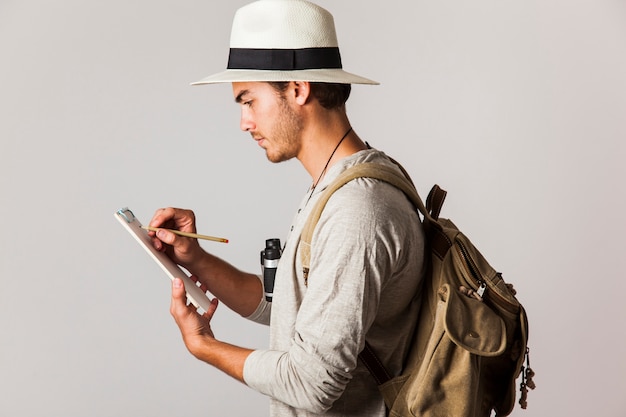 Hipster style tourist writing on clipboard