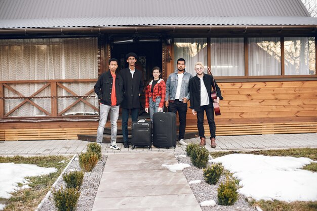 Hipster travellers ready for a trip. Indian men and woman holding suitcases at house.