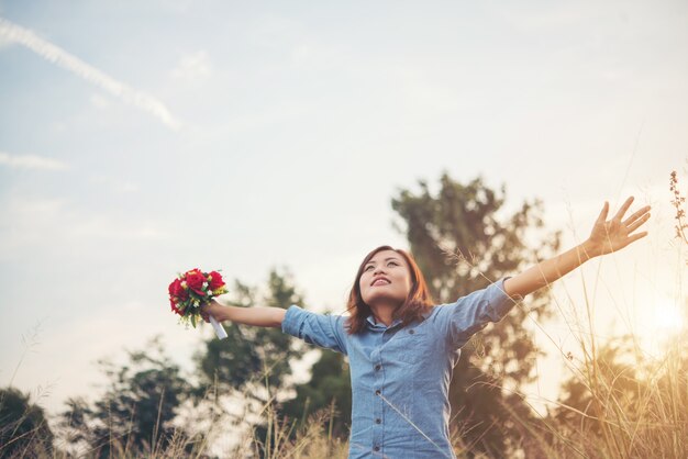 Hipster woman smile enjoy with fresh air raising arm in summer field, vintage tone filter.