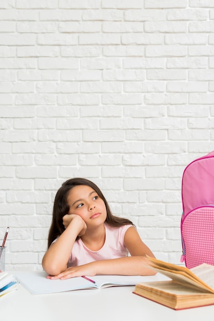 Hispanic bored schoolgirl sitting at desk