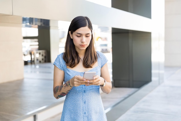 Hispanic brunette blogging through mobile phone at mall