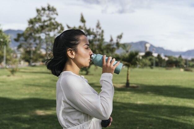 Hispanic female resting by drinking water after yoga practice