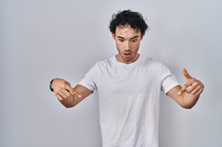 Free Photo hispanic man standing over isolated background pointing down with fingers showing advertisement surprised face and open mouth