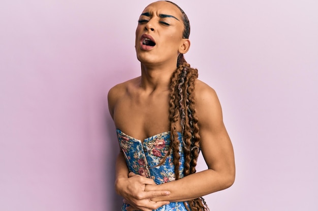 Free photo hispanic man wearing make up and long hair wearing elegant corset with hand on stomach because nausea painful disease feeling unwell ache concept