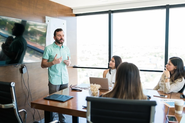 Hispanic manager sharing ideas with team in meeting room at office