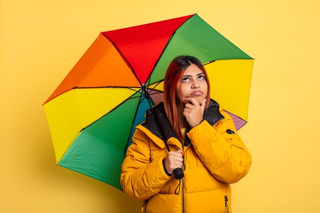 Латиноамериканка думает, чувствует сомнения и растерянность. концепция дождя и зонтика