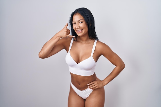 Free photo hispanic woman wearing lingerie smiling doing phone gesture with hand and fingers like talking on the telephone communicating concepts