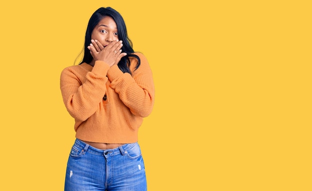 Free photo hispanic woman with long hair wearing casual winter sweater shocked covering mouth with hands for mistake secret concept