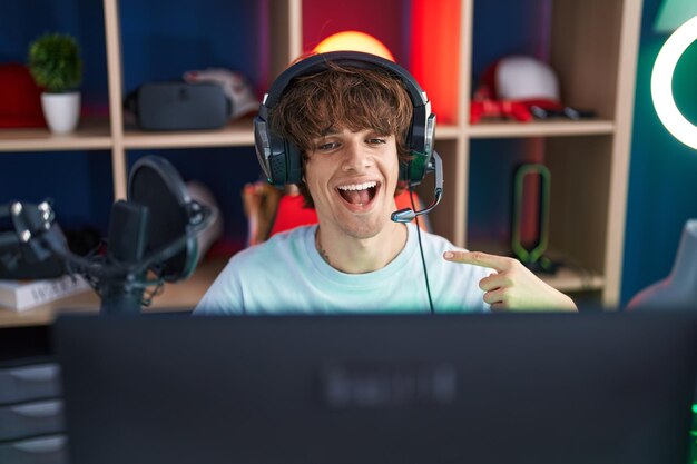 Hispanic young man playing video games smiling happy pointing with hand and finger