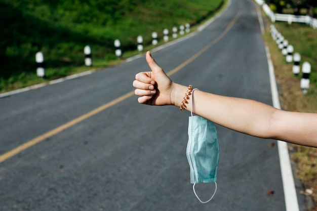 Free photo hitchhiker holding medical mask on a highway