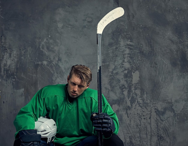 Free photo hockey player wearing black protective uniform holds a hockey stick on a gray background.