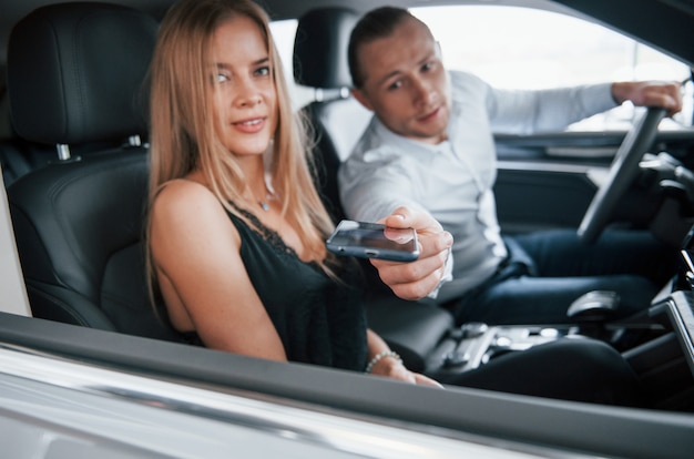 Hold my phone for a moment. Positive manager showing features of the new car to female customer