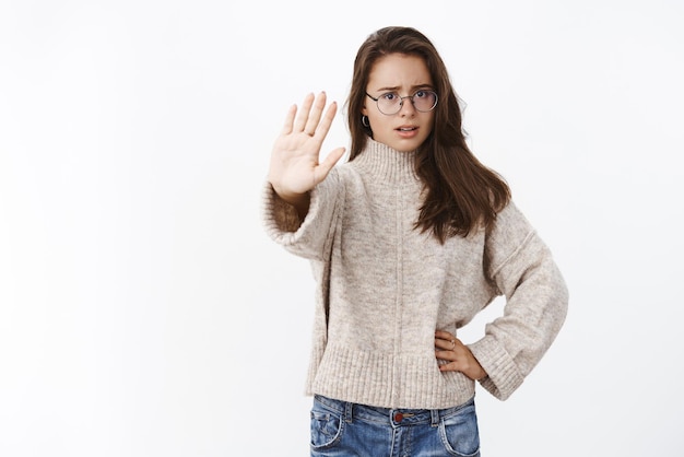 Hold stop right here Portrait of worried and displeased young female friend preventing girl sit in car drunk pulling palm towards camera in no prohibition gesture worrying for safety over gray wall