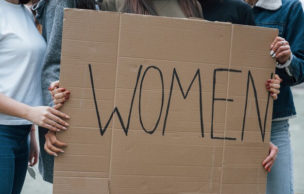 Holding big poster. Group of feminist women have protest for their rights outdoors