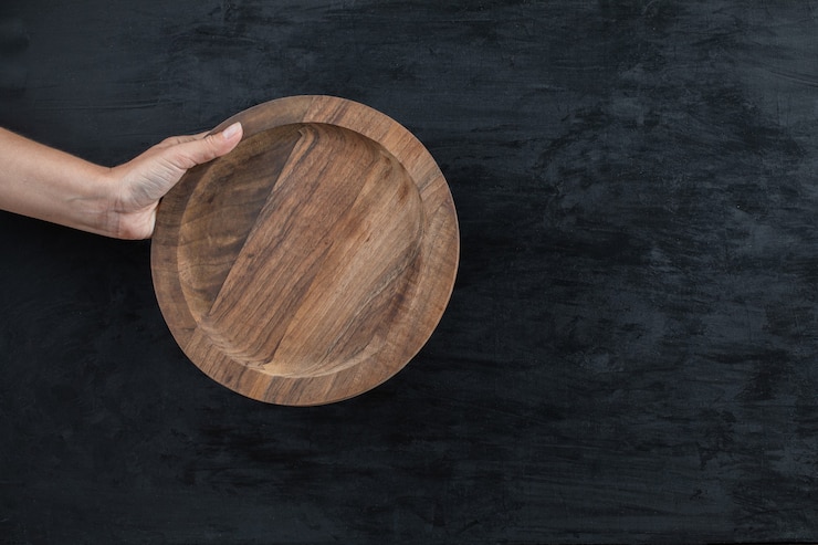 Free Photo holding a circle wooden platter with the hand