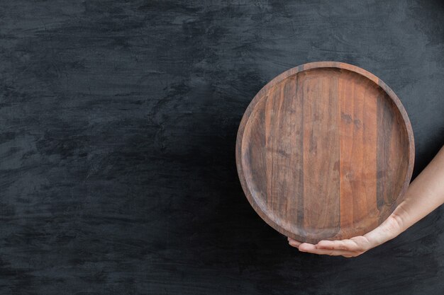 Holding a circle wooden platter with the hand