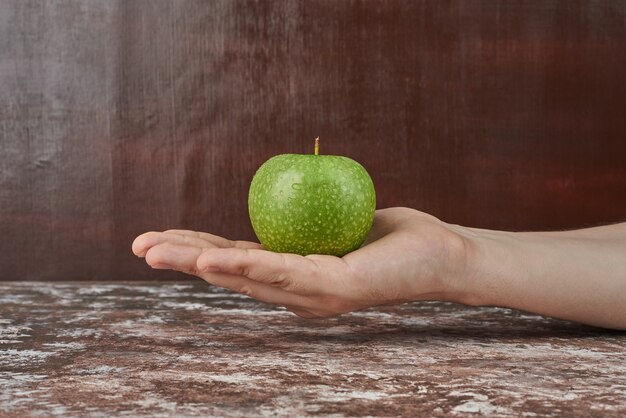 Holding green apple in the hand.