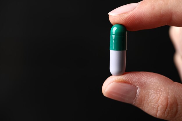 Holding a green medical pill.