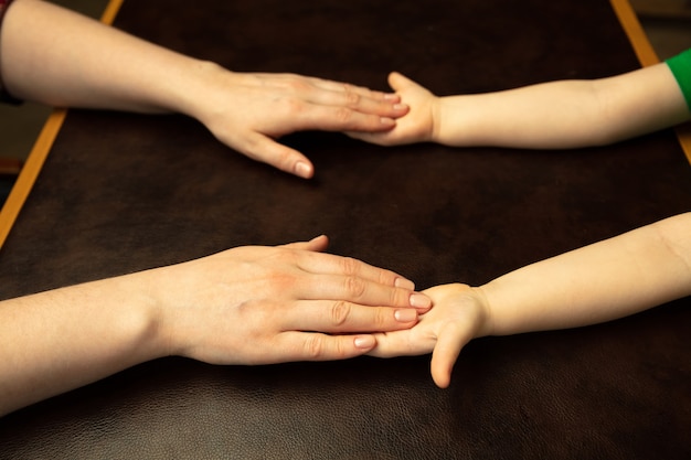 Free photo holding hands, clapping like friends. close up shot of female and kid's hands doing different things together. family, home, education, childhood, charity concept. mother and son or daughter, wealth.