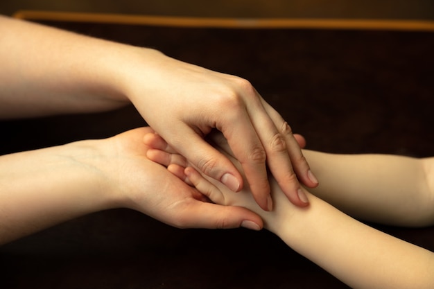 Holding hands, clapping like friends. Close up shot of female and kid's hands doing different things together. Family, home, education, childhood, charity concept. Mother and son or daughter, wealth.