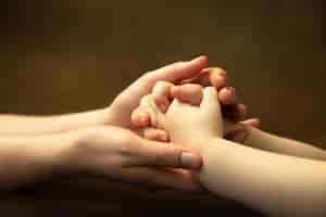 Free photo holding hands, clapping like friends. close up shot of female and kid's hands doing different things together. family, home, education, childhood, charity concept. mother and son or daughter, wealth.