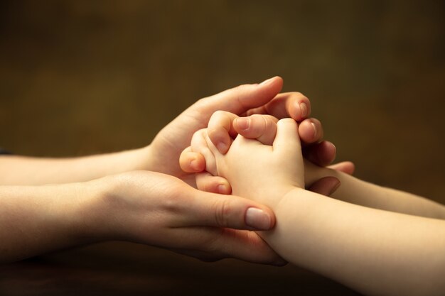 Holding hands, clapping like friends. Close up shot of female and kid's hands doing different things together. Family, home, education, childhood, charity concept. Mother and son or daughter, wealth.