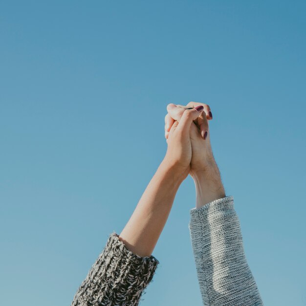 Holding hands in front of sky