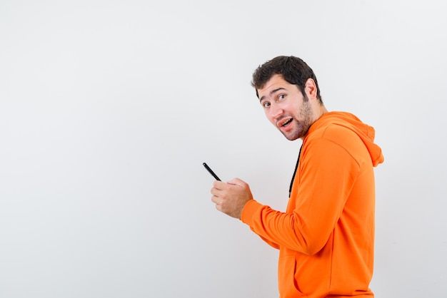 Мужчина с мобильным телефоном смотрит в камеру на белом фоне
