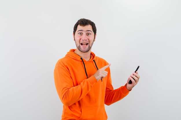 Мужчина с мобильным телефоном показывает его указательным пальцем на белом фоне