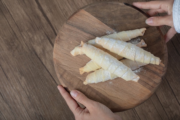 Holding mutaki cookies on a wooden board in the hand.