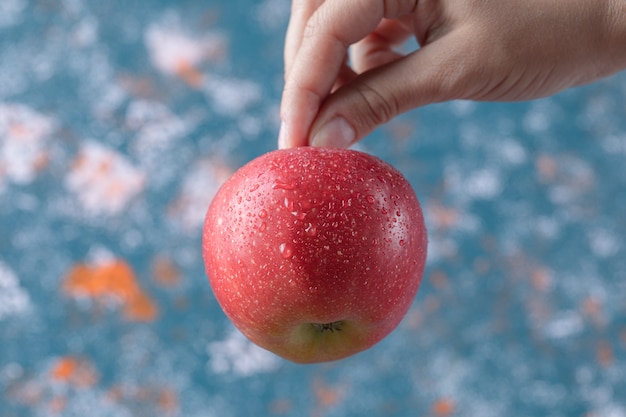 Holding a red apple from stem