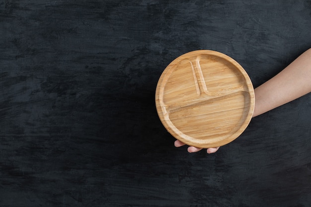 Holding a round wooden platter in the hand