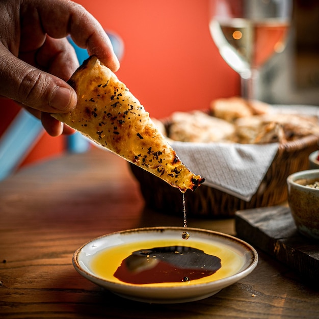 Holding a slice of bread with thyme and dipping it to oil