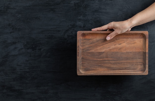 Holding a square wooden board on black background