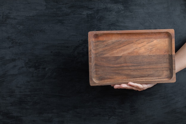 Holding a square wooden platter in the hand