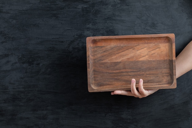 Holding a square wooden platter with the hand