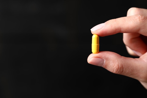 Holding a yellow medical pill.