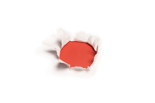 A hole in a white paper on a red background, copy space.