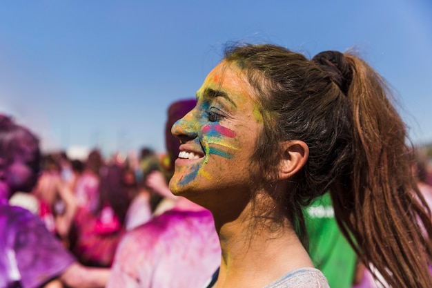 Holi color on woman's face in front of crowd